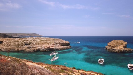 Fototapeta premium Comino, Malta 29.05.2024 - Boats anchored near Blue lagoon, Cominotto island in the back. Revealing shot. High quality photo