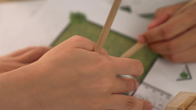 A video of architect using ruler and pencil to measure blueprint scale. Designer designing house construction on a table at studio with architectural plan scattered around. Focus on hand. Delineation.