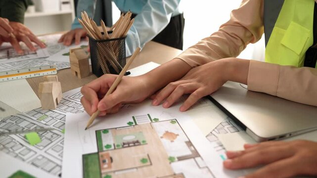 Smart architect and safety engineer discussion about building blueprint on table with architectural document, measurement tools and wooden block scatter around at modern office. Closeup. Delineation.