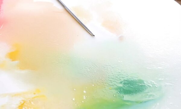  The camera records the gradual drying process of a watercolor painting, as the colors settle and soften. The pigments lighten and the water evaporates, revealing the final, beautifully abstract patte