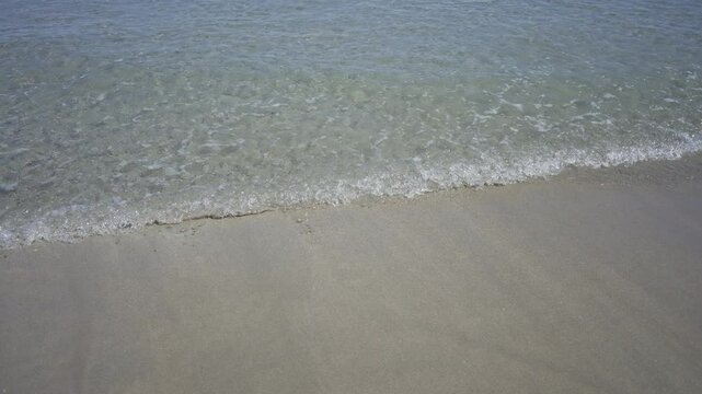 Serene beach with gentle waves lapping against the sandy shore, creating a peaceful seaside ambiance in a clear and calm outdoor setting.