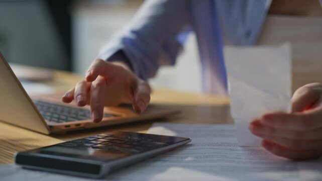 Woman calculating checks home office using calculator closeup. Businesswoman