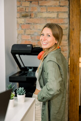 Smiling woman standing by a copier in a modern office
