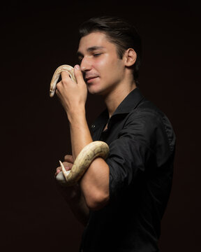 portrait of a man with a yellow python.happy man holding a yellow python on a dark background
