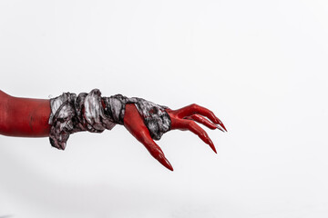 A terrifying red demon hand wrapped in a shroud, reaching out menacingly on a white studio background. This eerie, Halloween-themed image evokes fear and horror with its ghostly, undead appearance.