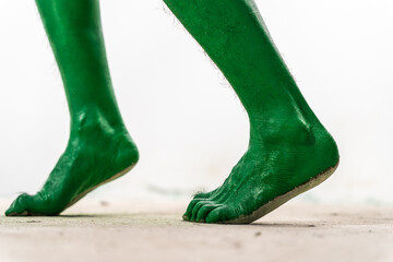 A close-up studio shot of a green, zombie-like foot isolated on a white background. The foot appears eerie and spooky, evoking Halloween vibes with its ghastly, horror-themed appearance.