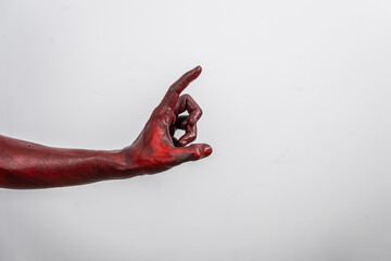 A terrifying red demon hand, reaching out menacingly on white studio background. The eerie, Halloween-themed image exudes horror, capturing the essence of fear, death, the undead in ghostly scene.