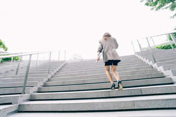 Asian business woman walking to work diligently and briskly in morning in a big city. female in a business suit, dressed in a smart suit, runs to work during rush hour in corridors and stairs.