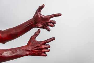 A terrifying red demon hand, reaching out menacingly on white studio background. The eerie, Halloween-themed image exudes horror, capturing the essence of fear, death, the undead in ghostly scene.
