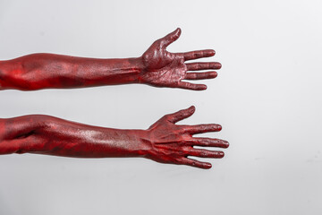 A terrifying red demon hand, reaching out menacingly on white studio background. The eerie, Halloween-themed image exudes horror, capturing the essence of fear, death, the undead in ghostly scene.