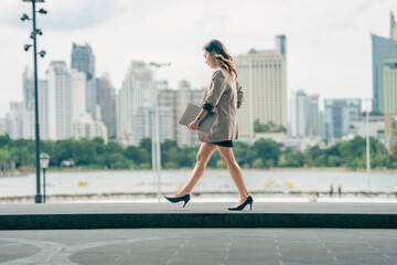 Asian business woman walking to work diligently and briskly in morning in a big city. female in a...