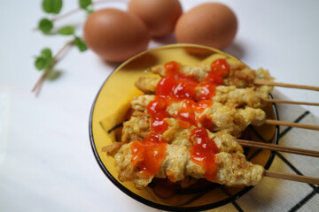 Telur Gulung or Tolled Egg served on a plate with chilli sauce. Rolled Egg Omelette with Skewers. Popular Street Food in Indonesia.