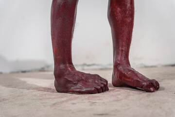 Dirty and horrifying red zombie feet displayed on white studio background. The gruesome Halloween-themed image emphasizes fear and shock, capturing the grotesque and unsettling nature of the undead.