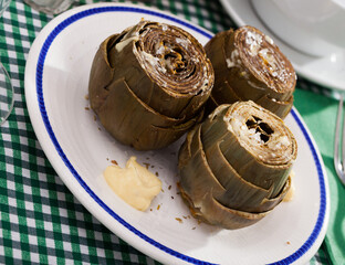 Delicious steamed artichoke with alioli sauce on a white plate