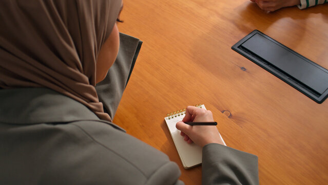 Woman in hijab Writing in Notebook at Desk