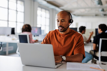 Focused male customer service representative working on laptop