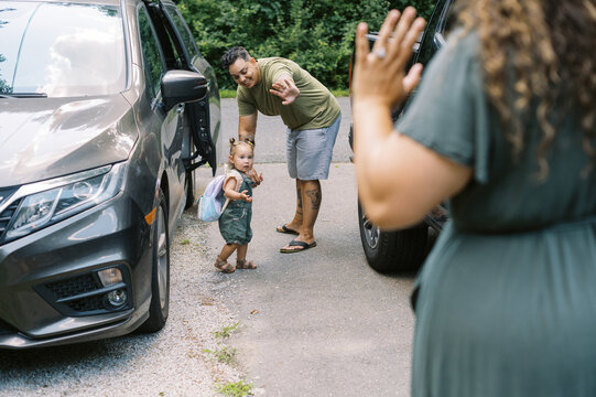 mom waving goodbye to wife and toddler daughter in driveway