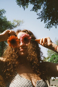 A woman with two flowers covering her eyes