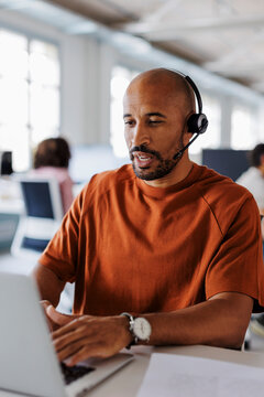 Focused male customer service representative working on laptop