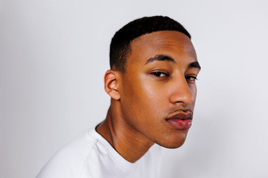 Serious young adult male model posing on white background