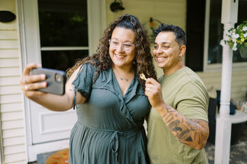 smiling lgbtq couple taking selfie with key and new house