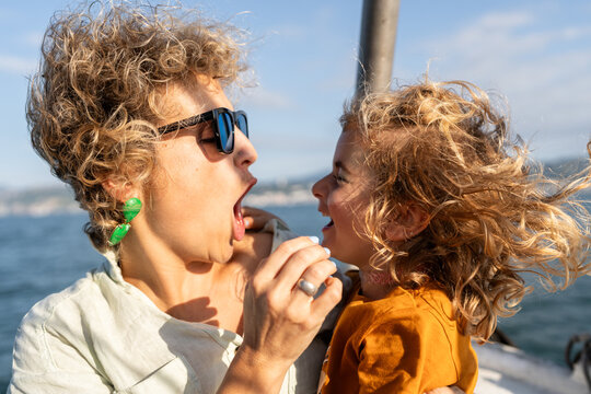 Mother and daughter making funny faces while enjoying boat trip