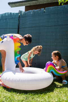Mother and daughters preparing inflatable unicorn pool float