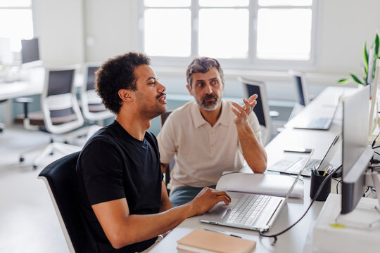 Two male software developers discussing project in bright office