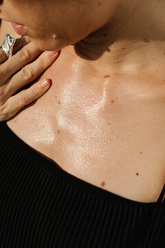 A detailed shot of a woman's chest and neck, illuminated by sunlight