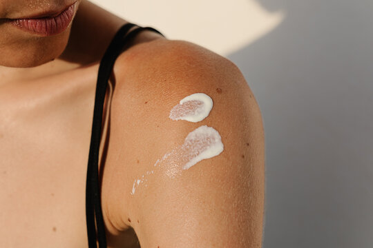 Shoulder of an unidentified woman with sunscreen applied to her skin