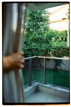 Ugc pov film photo of a hand holding a curtain to look into backyard