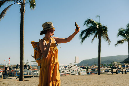 Woman waving while connecting through her smartphone during summ