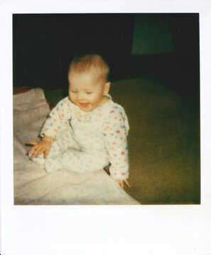 Baby sitting and smiling on a blanke