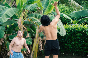 Group of Young Adults Playing Volleyball in Tropical Field