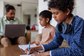 Brother writing in book by sister studying at home