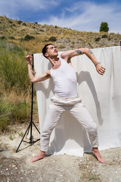 dancer with tattoos is posing in nature with white backdrop