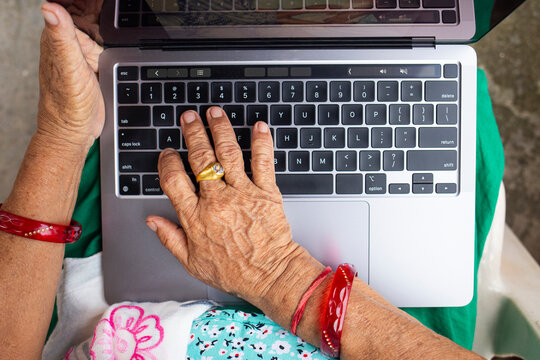Close-up of an elderly woman's hand on a laptop keyboard
