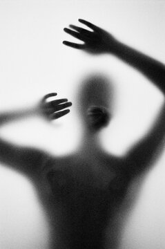 The silhouette of a person is visible through a frosted window. 