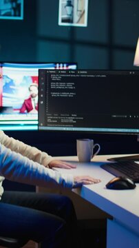 Vertical video Programmer stretches body limbs after securing company servers from virus attacks all day. Fatigued IT remote employee relaxing tense muscles at desk after building firewalls protecting