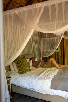 Male tourist relaxing on his bed in a safari tent in South Africa