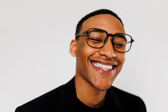 Man wearing glasses laughing on white background