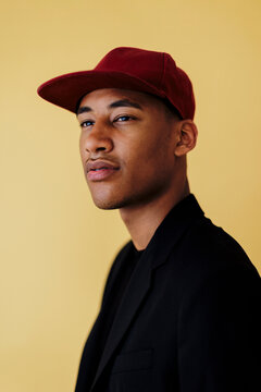 Man wearing red cap and black jacket posing in studio