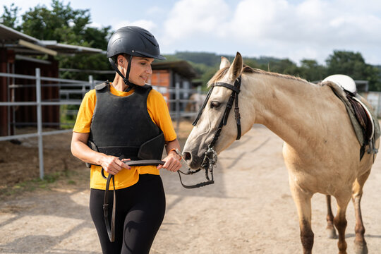 Female jockey preparing horse for training on ranch