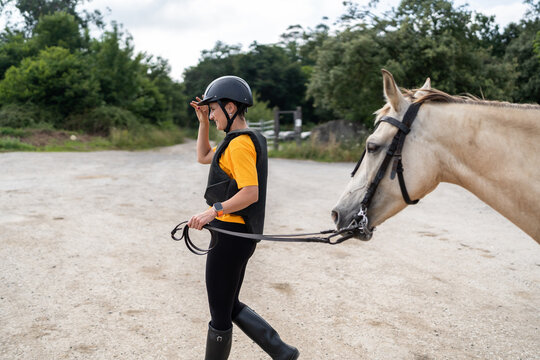 Horse riding training - woman jockey walking with horse in countryside