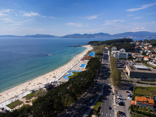 Aerial view of Playa de Samil, the main beach of Vigo in Galicia in northwest Spain. Sunny day, crystal clear blue sea. Houses, streets. Drone