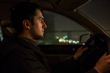 Young man driving car in the night