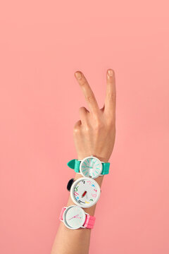A woman's hand with watches with two fingers up, making a V sign.