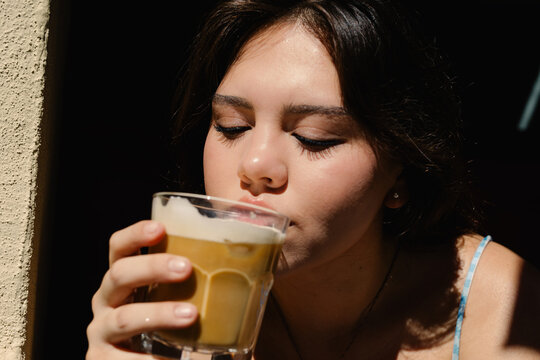 A young woman relishing a latte on a bright summer day