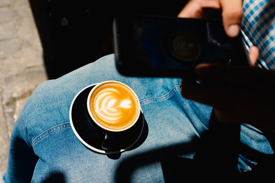 Anonymous woman using her smartphone to take a picture of a latte art