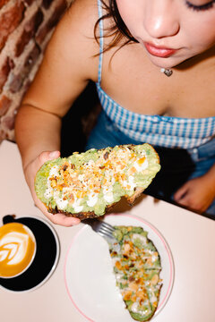 Overhead shot lit with direct flash of a woman enjoying avocado toast